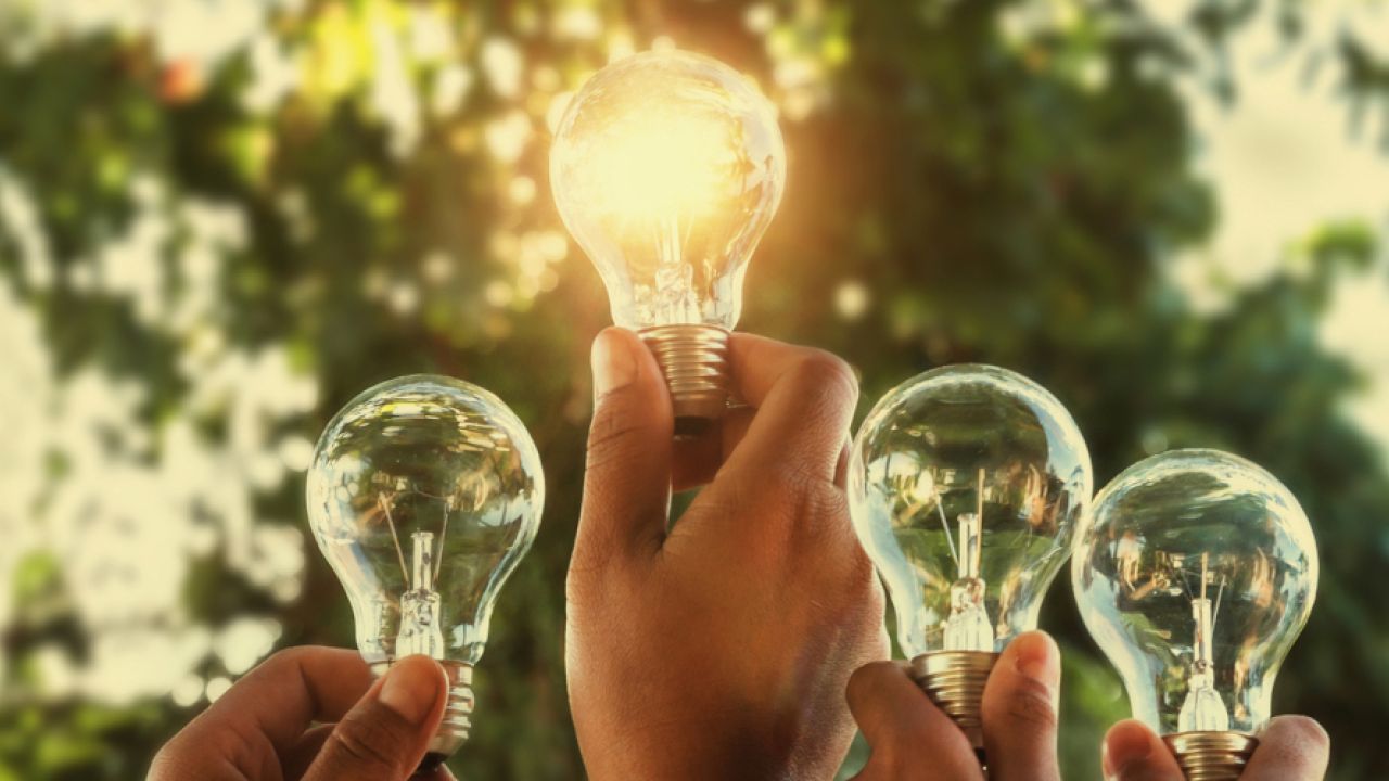 solar energy concept hand group holding light bulb in nature